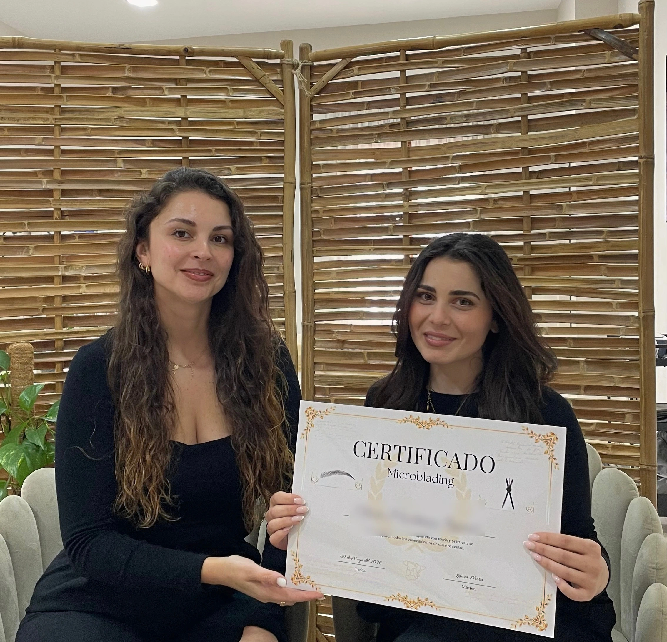 Laura Mora entregando un certificado de su formación de microblading a una alumna en su estudio
